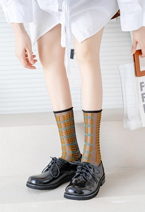 Detail of brown mesh crew socks with yellow dots and blue stripes worn with oxford shoes
