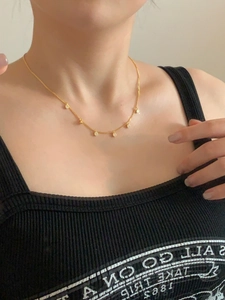 Close-up of golden necklace with five round sparkling zircon pendants on a model