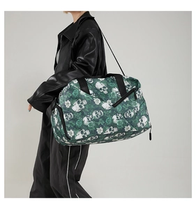 Detail of green travel bag with skull and rose print worn by model in black leather jacket