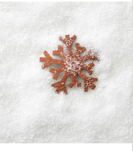 Détail d'un pendentif flocon de neige en bois brun sur fond de neige artificielle