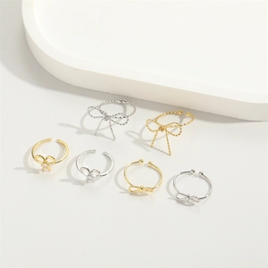 Close-up of six minimalist bow-shaped open rings in gold and silver metal finishes
