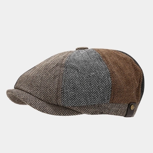 Detail of herringbone wool newsboy cap with brown leather strap and metal button trim
