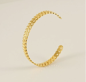 Detail of gold C-shaped stainless steel bracelet with double row chain texture