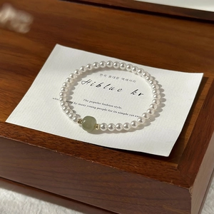 Detailed shot of pearl bracelet with green jade bead on a minimalist display card