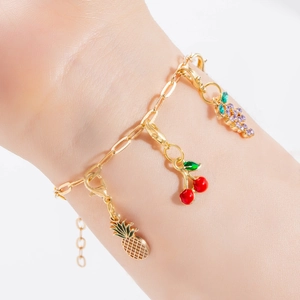 Detailed shot of fruit charms on a gold chain bracelet with enamel and rhinestones