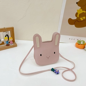 Pink rabbit crossbody bag for kids featuring floral clip and cute embroidery on white table