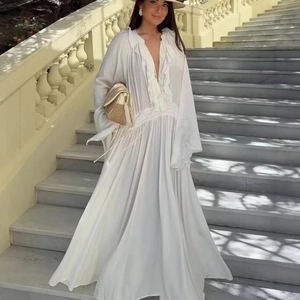Robe longue blanche élégante avec col en V, volants et manches amples pour les vacances