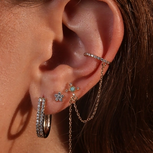 Macro detail of gold earrings set featuring star studs and turquoise accents