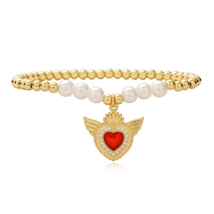 Golden beaded bracelet with pearls and red heart wing charm on white background