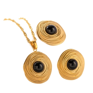 Vintage gold coil jewelry set with concentric texture and black onyx inlay on white background