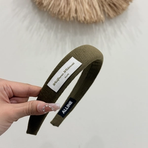 Close-up of deep green padded fabric headband with textured finish and woven label detail
