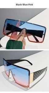 Detail of square oversized black sunglasses with blue pink gradient lenses and gold hinges