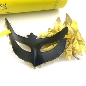 Detail of Venetian masquerade mask featuring black matte base with golden lace and side feathers