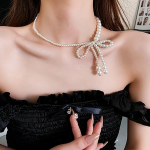 Dettaglio della collana di perle con fiocco su una modella che mostra lo stile francese