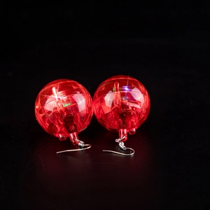 Glow-in-the-dark red disco ball earrings with LED light and metal hook on black background