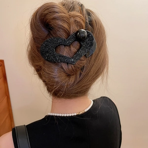 Detail of a black heart hair claw clip with shimmering rhinestones on a female model