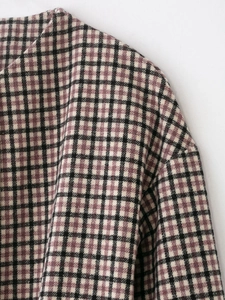 Close-up of the vintage plaid fabric texture and collar stitching on the long coat