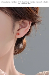Close-up of S999 silver stud earring featuring an orange-red round gemstone in 4-prong setting