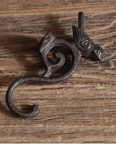 Detalle de un gancho de pájaro de hierro fundido rústico con volutas vintage en marrón oscuro
