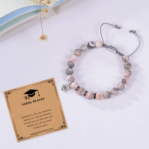 Close-up of pink zebra stone beads and compass charm on adjustable braided bracelet