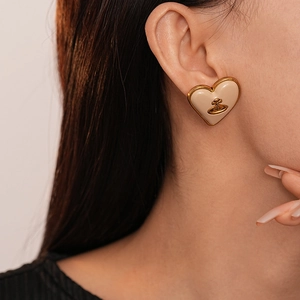 Détail de boucles d'oreilles cœur crème vintage avec motif Saturne doré pour femme