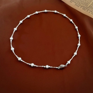 Macro shot of silver twisted metal chain links and elegant white pearls necklace