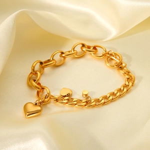 Close-up of 18K gold plated Cuban chain bracelet with heart pendant on silk background