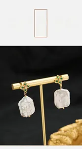 Detailed close-up of Baroque pearl earrings with green zircon and gold plating