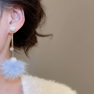 Detail of light blue pompom and pearl drop earring worn showing elegant drape and texture