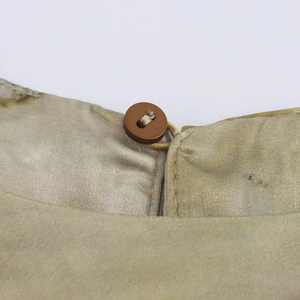 Detail shot of the back collar showing a dark resin button on silky champagne satin fabric