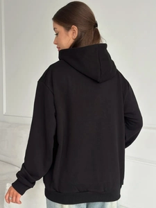 Back view of a black oversized zip-up hoodie featuring a large hood and dropped shoulders