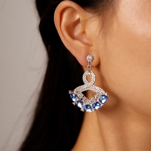 Detail of luxury geometric silver drop earrings with blue rhinestones on model