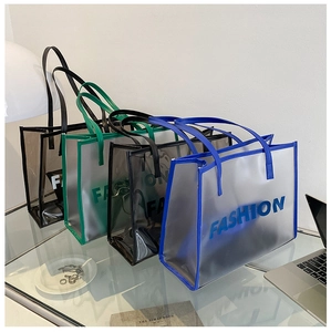 Transparent PVC tote bags in blue, green, black and grey displayed on a glass table
