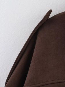 Detailed close-up of dark brown suede texture and stitching on an aviator jacket
