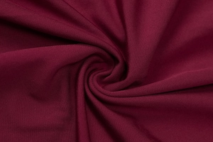 Close-up of wine red textured knit fabric showing fine ribbed patterns and elegant drape