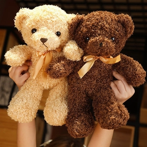 Close-up of small teddy bear plush shells in beige and coffee with gold satin bows