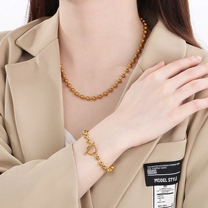 Close-up of golden stainless steel ball chain necklace and bracelet with heart toggle clasp