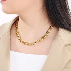 Gros plan d'un collier chaîne Figaro doré porté par un mannequin en costume beige élégant
