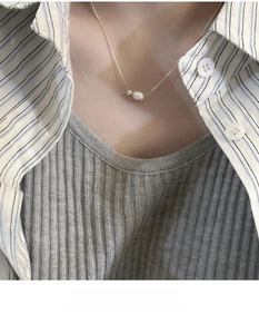 Close-up of a s925 sterling silver chain with a baroque pearl pendant on a model