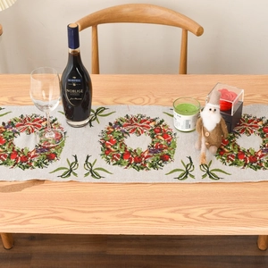 Detailed view of Christmas table runner with festive berry wreath and green bow pattern