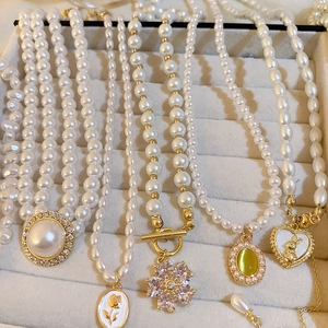 Détail de colliers de perles françaises avec pendentifs rose et cœur en boîte à bijoux