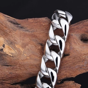 Gros plan détaillé d'un bracelet gourmette en acier inoxydable poli sur un bois naturel