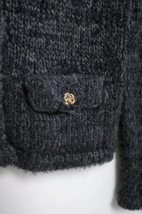 Gros plan d'un cardigan gris foncé en maille épaisse avec des boutons dorés tressés