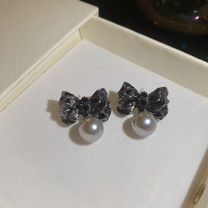 Vue macro détaillée de boucles d'oreilles nœud plissé noir avec une perle gris argenté