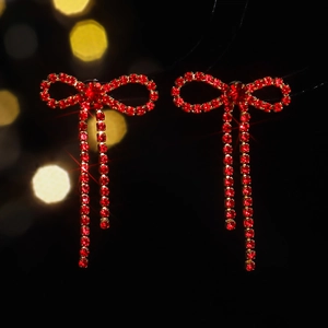 Close-up of red rhinestone bow earrings with long sparkling tassel drops