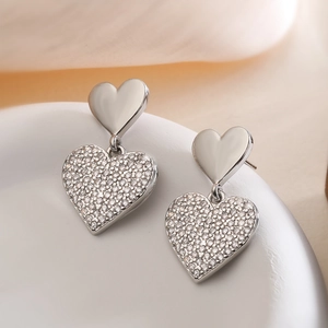 Close-up of silver geometric heart drop earrings with white pavé zirconia stones