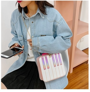 Detail of a pink and white piano-themed crossbody bag with holographic keys and gold chain