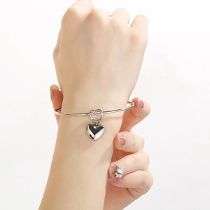 Bracelet jon jonc noué argenté avec pendentif cœur porté sur fond blanc épuré