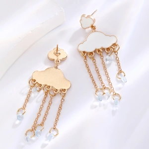Detalle de pendientes de nube en esmalte blanco con borlas doradas y gotas de lluvia azul