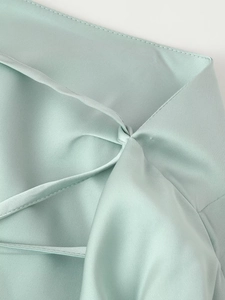 Dettaglio dell'abito in raso verde menta con design stringato e tessuto lucido effetto seta